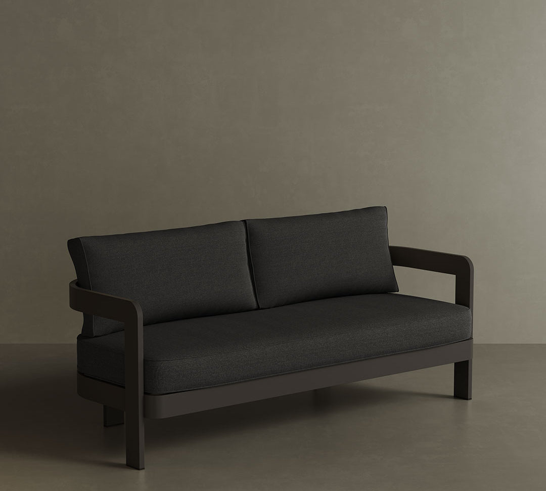 A sophisticated N3 three-seater sofa in Kohl Shadow canvas, featuring a modern design with durable, soft fabric. The sofa is supported by a sturdy aluminium frame, combining sleek style with lasting durability. Its deep, dark colour and contemporary aesthetic make it an ideal focal point for any outdoor space, offering both comfort and a refined, minimalist look.