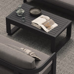 A luxury, kohl-colored aluminium outdoor table with a modern, dark aesthetic, styled alongside the N3 Kohl three-seater sofa in smoke weave and our H3 Fog rug. The sleek table, with its smooth matte finish and clean lines, complements the sophisticated, contemporary design of the sofa and rug, creating an effortlessly chic and cohesive outdoor living space.