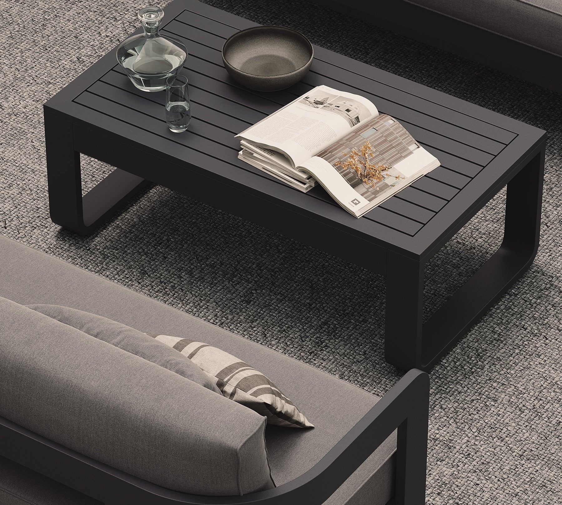 A luxury, kohl-colored aluminium outdoor table with a modern, dark aesthetic, styled alongside the N3 Kohl three-seater sofa in smoke weave and our H3 Fog rug. The sleek table, with its smooth matte finish and clean lines, complements the sophisticated, contemporary design of the sofa and rug, creating an effortlessly chic and cohesive outdoor living space.