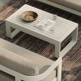 A luxurious stone-coloured outdoor coffee table with a sleek aluminium frame, styled alongside the N3 three-seater sofa in sand canvas fabric and the H1 biscuit rug. The table’s elegant stone finish and modern aluminium frame create a sophisticated focal point, perfectly complemented by the soft, neutral tones of the sofa and rug, forming a refined and inviting outdoor living space.