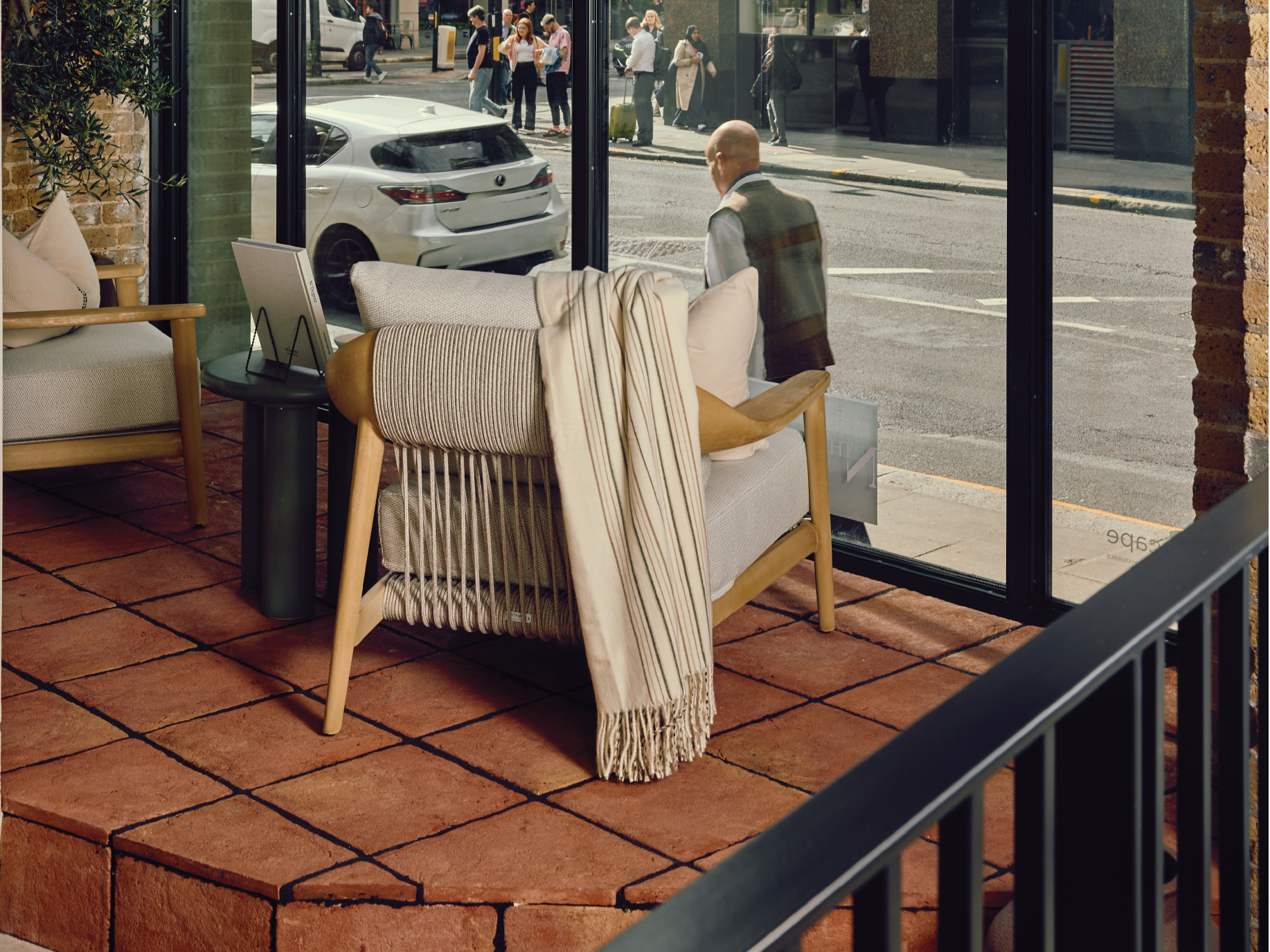 Back of an N1 teak chair with terracotta tiles below, with rope detailing and a tasseled cream throw hanging off the back.